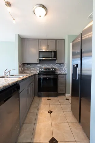 a kitchen with stainless steel appliances granite countertop a stove a sink and a refrigerator