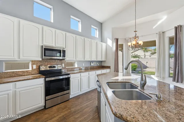 a kitchen with granite countertop a sink a counter space appliances and cabinets
