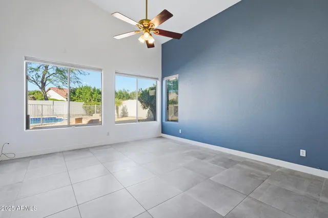 an empty room with windows and chandelier fan