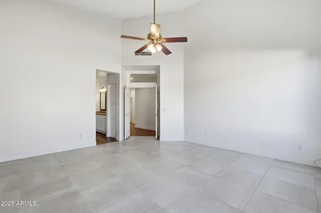an empty room with a chandelier fan and windows