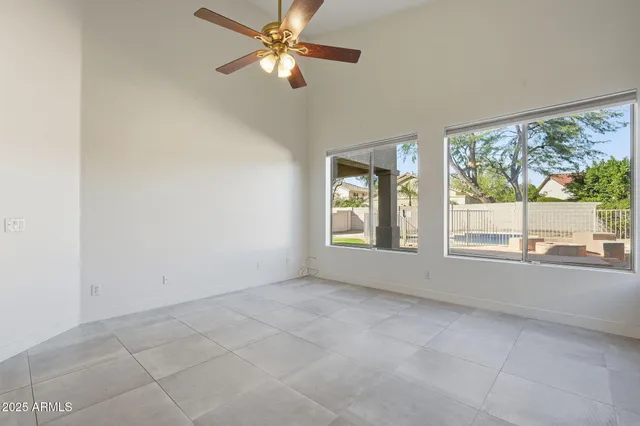 an empty room with chandelier fan and windows