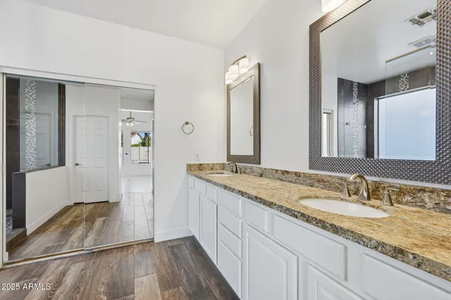 a bathroom with a granite countertop double vanity sink and mirror