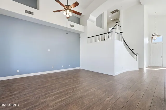 a view of an empty room with wooden floor and a ceiling fan