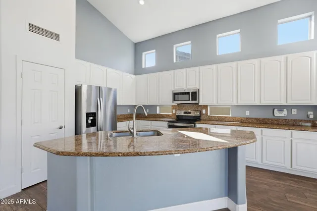 a kitchen with stainless steel appliances granite countertop a sink a stove a refrigerator a center island and cabinets