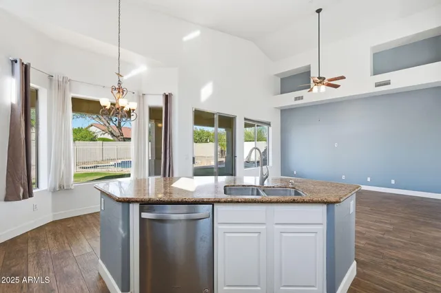 a kitchen with kitchen island granite countertop a sink cabinets and wooden floor