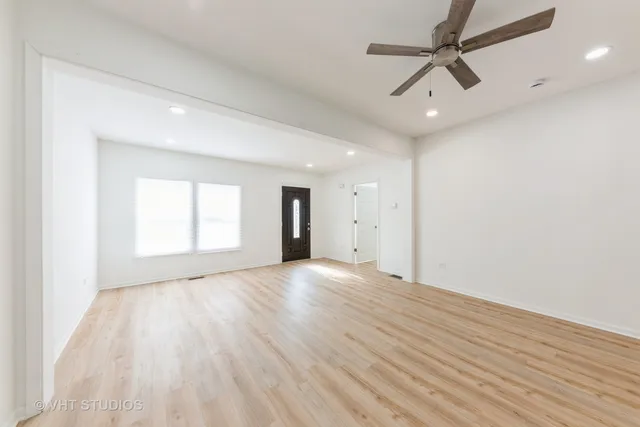 an empty room with wooden floor ceiling fan and windows