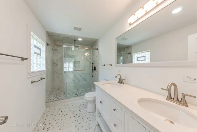 a bathroom with a double vanity sink mirror and shower