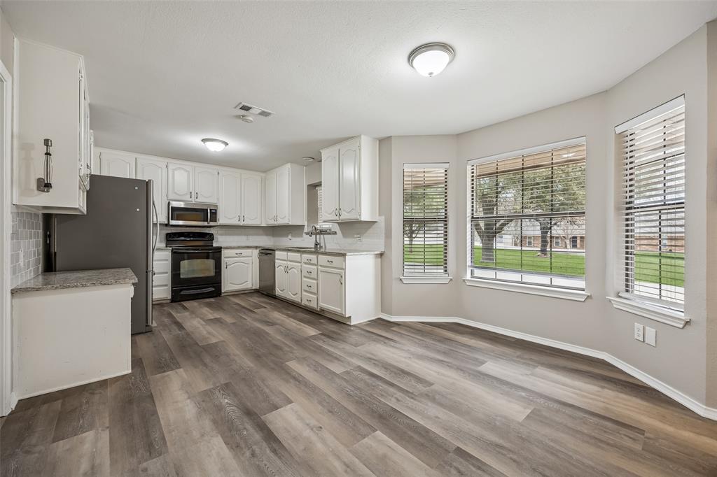 116 Timberview Court Burleson, TX 76028 - Photo 14 of 37 a kitchen with stainless steel appliances granite countertop a refrigerator oven a stove top oven and white cabinets with wooden floor