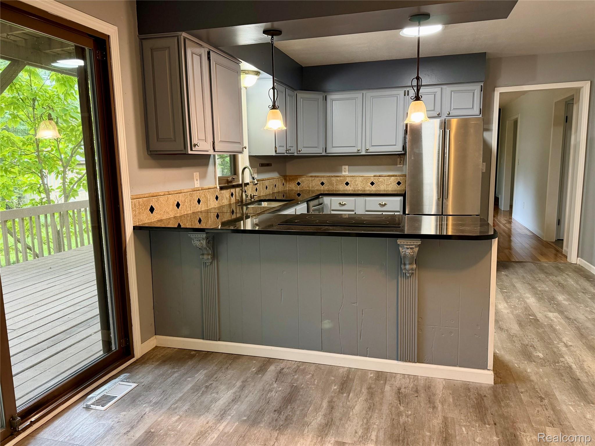10280 Nimphie Road Fenton, MI 48430 - Photo 8 of 30 Kitchen featuring light gray cabinetry, dark granite-style countertops, stainless steel refrigerator, and wood-finish flooring