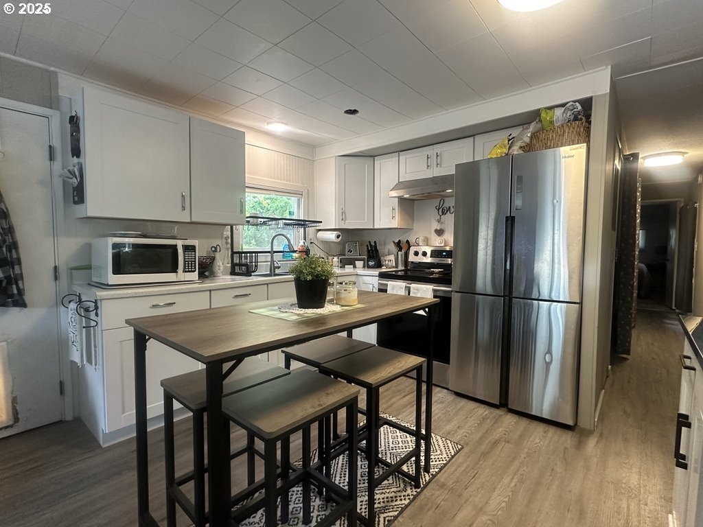 4875 Highway 101, Unit 93 Depoe Bay, OR 97341 - Photo 3 of 13 a kitchen with stainless steel appliances a refrigerator a stove a sink dishwasher a dining table and chairs with wooden floor