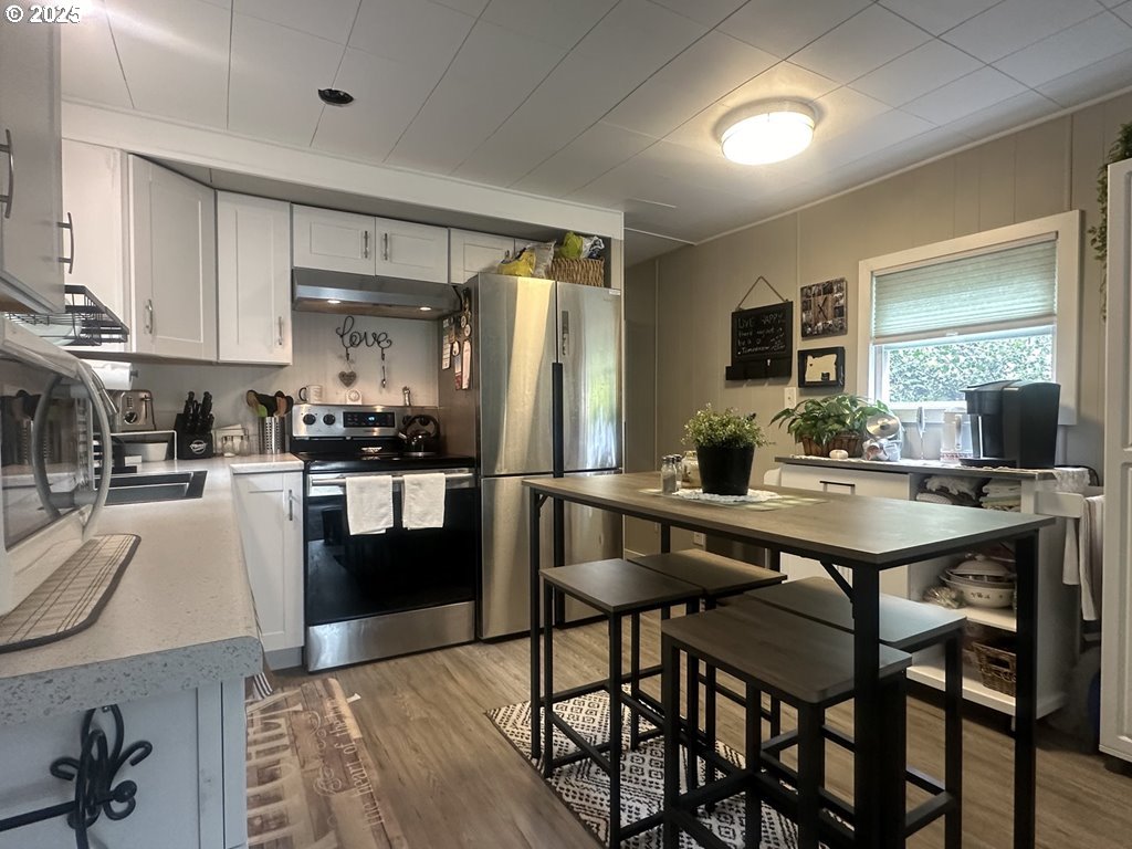 4875 Highway 101, Unit 93 Depoe Bay, OR 97341 - Photo 4 of 13 a kitchen with stainless steel appliances granite countertop a stove a refrigerator a sink a stove and white cabinets with wooden floor