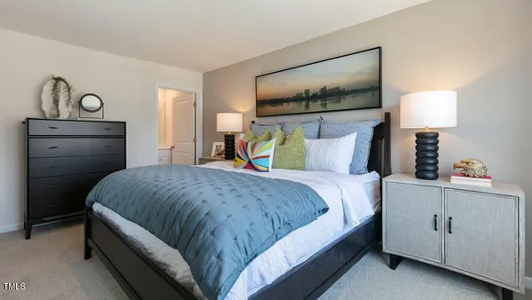 a bedroom with a bed and a lamp on dresser