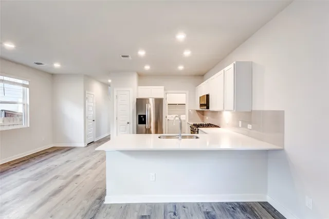 a large white kitchen with kitchen island a sink appliances and a counter top space