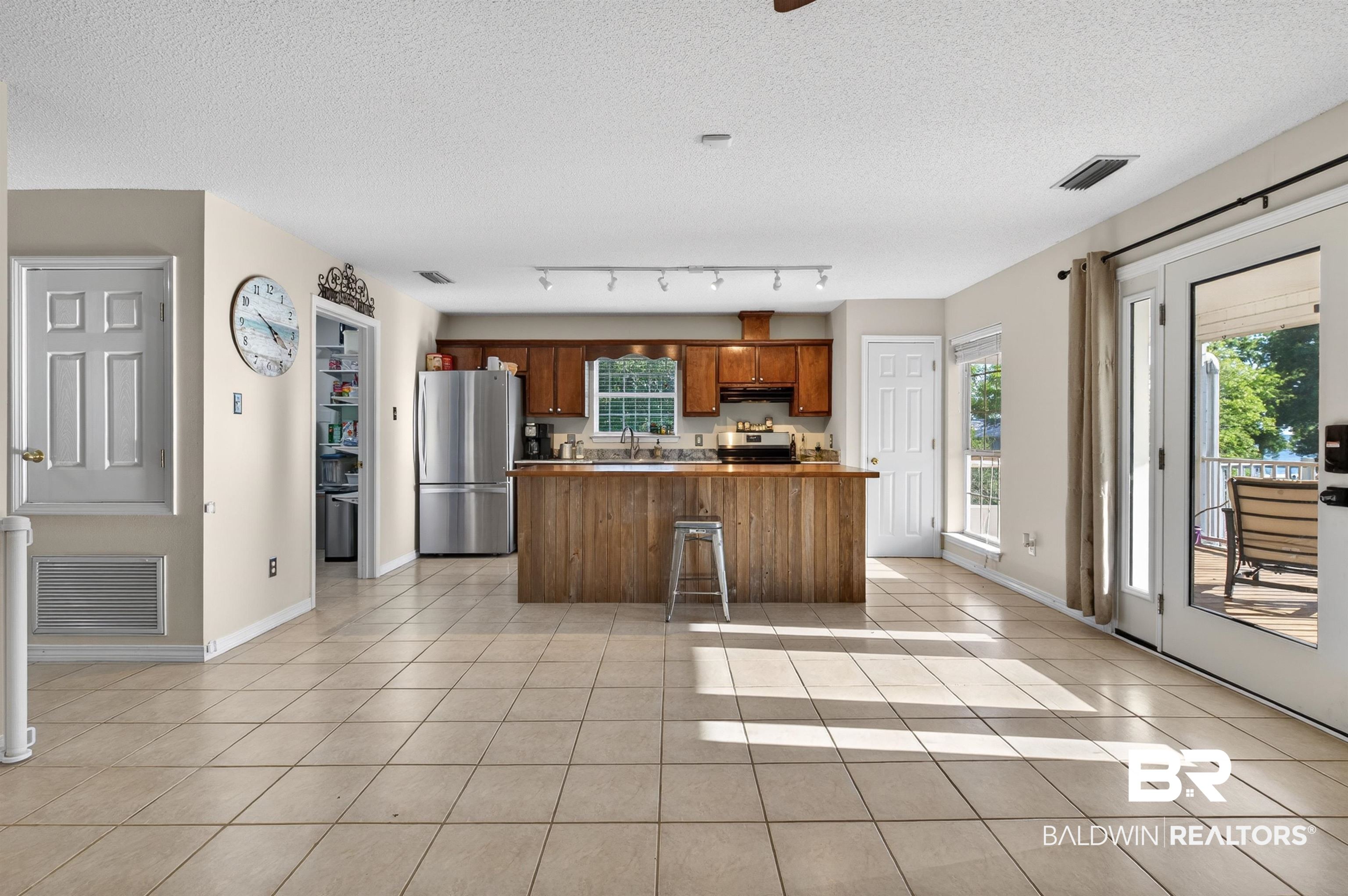9624 North Bay Street Foley, AL 36535 - Photo 9 of 59 Open-concept living area with tile flooring throughout, featuring a kitchen with wood cabinetry and stainless steel appliances