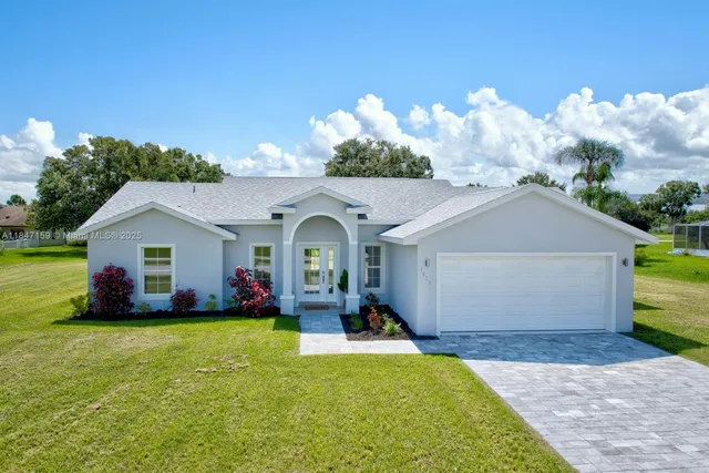 a front view of house with yard and trees in the background