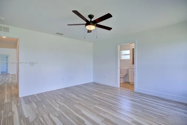 an empty room with wooden floor and ceiling fan