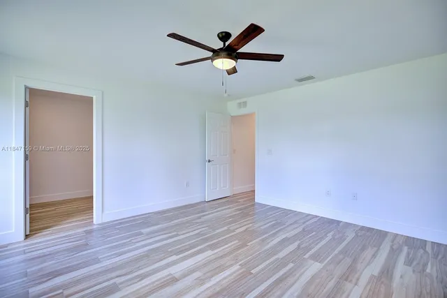 an empty room with wooden floor and a ceiling fan
