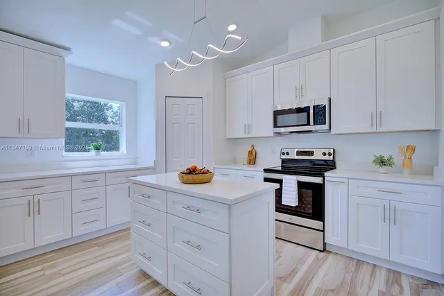a kitchen with white cabinets and appliances