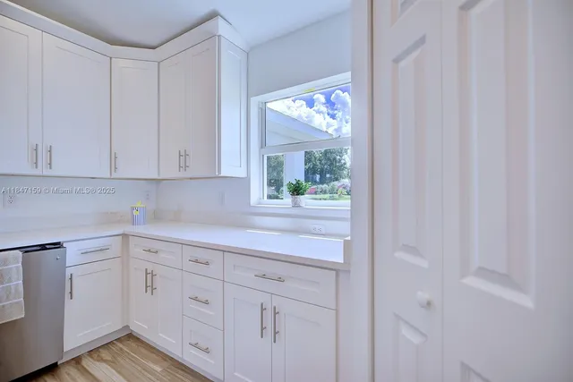 a kitchen with white cabinets and a window