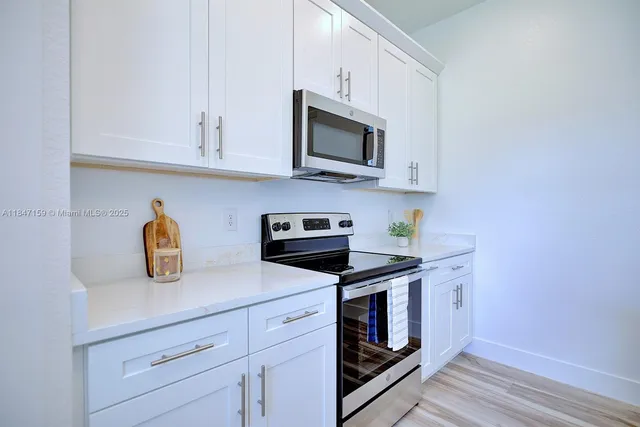 a kitchen with stainless steel appliances granite countertop a sink a stove and microwave with wooden floor