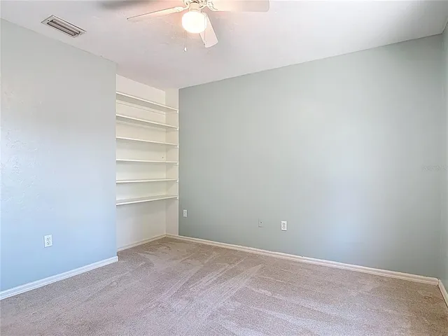an empty room with fan and windows