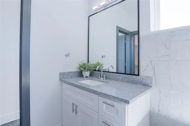 a bathroom with a granite countertop sink and a mirror