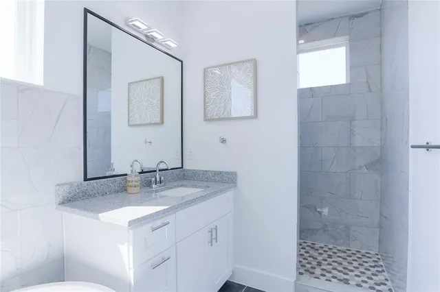 a bathroom with a shower sink vanity and mirror