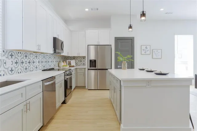 a kitchen with white cabinets and stainless steel appliances