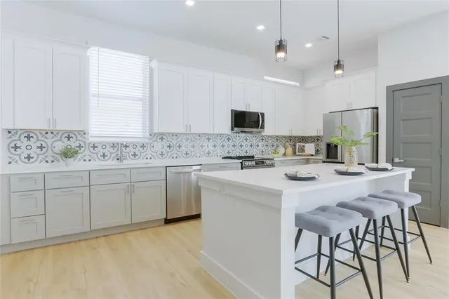 a kitchen with cabinets a sink stainless steel appliances and window