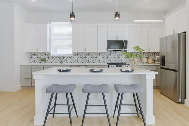a kitchen with stainless steel appliances a dining table chairs and refrigerator