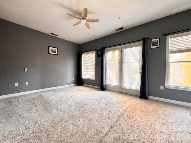 an empty room with windows and ceiling fan