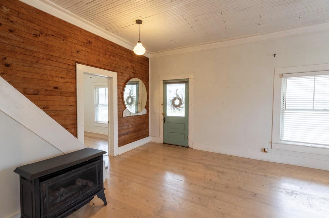 Foyer with light wood-style floors, a wood stove, and ornamental molding