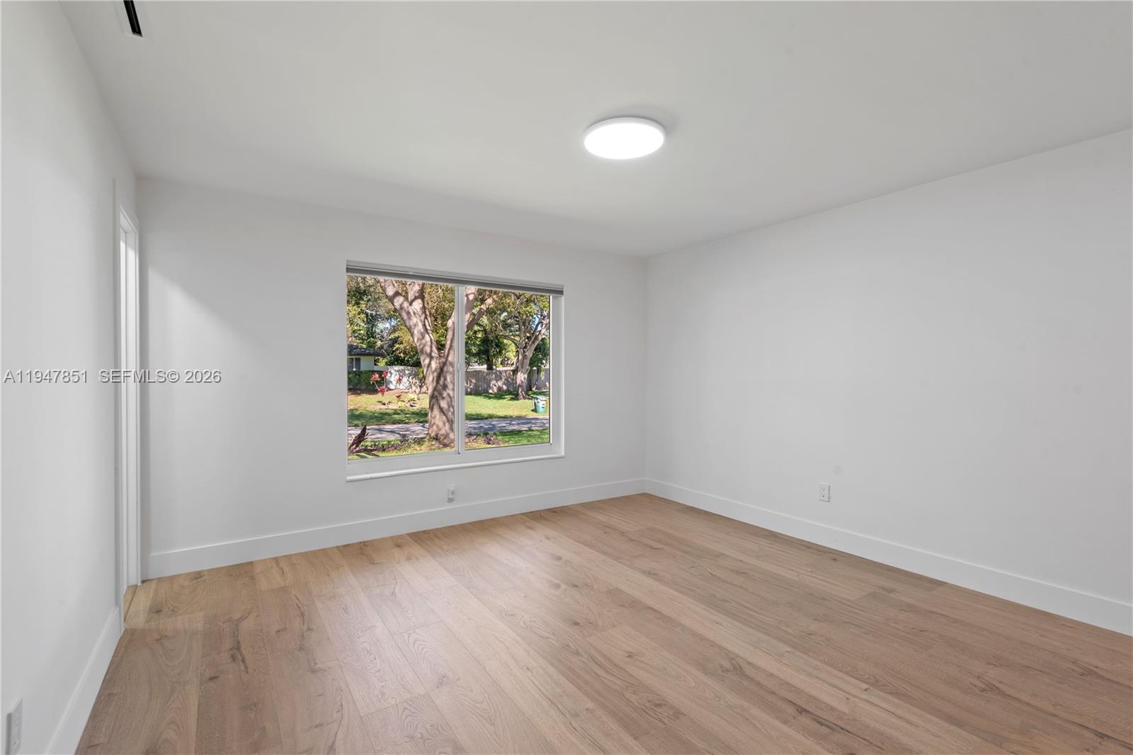 8420 Southwest 179th Street Palmetto Bay, FL 33157 - Photo 11 of 27 a view of an empty room with wooden floor and a window