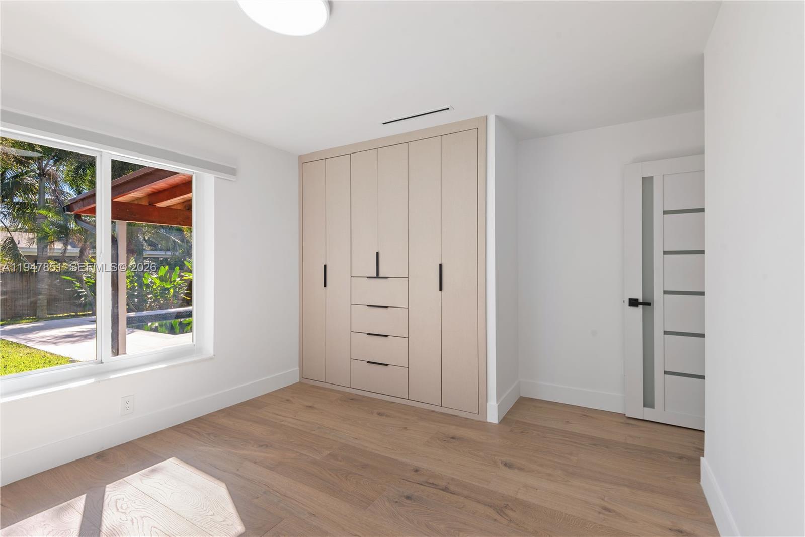 8420 Southwest 179th Street Palmetto Bay, FL 33157 - Photo 15 of 27 an empty room with wooden floor and windows