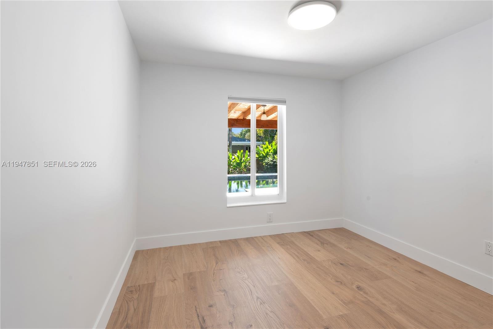 8420 Southwest 179th Street Palmetto Bay, FL 33157 - Photo 18 of 27 an empty room with wooden floor and windows