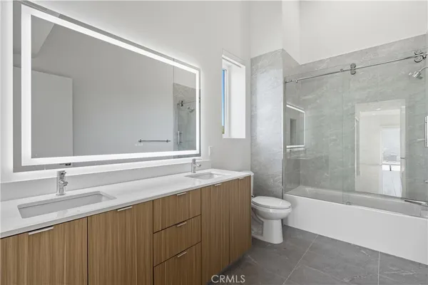 a bathroom with a sink a toilet a mirror and shower