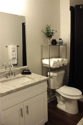 a bathroom with a granite countertop toilet sink and mirror