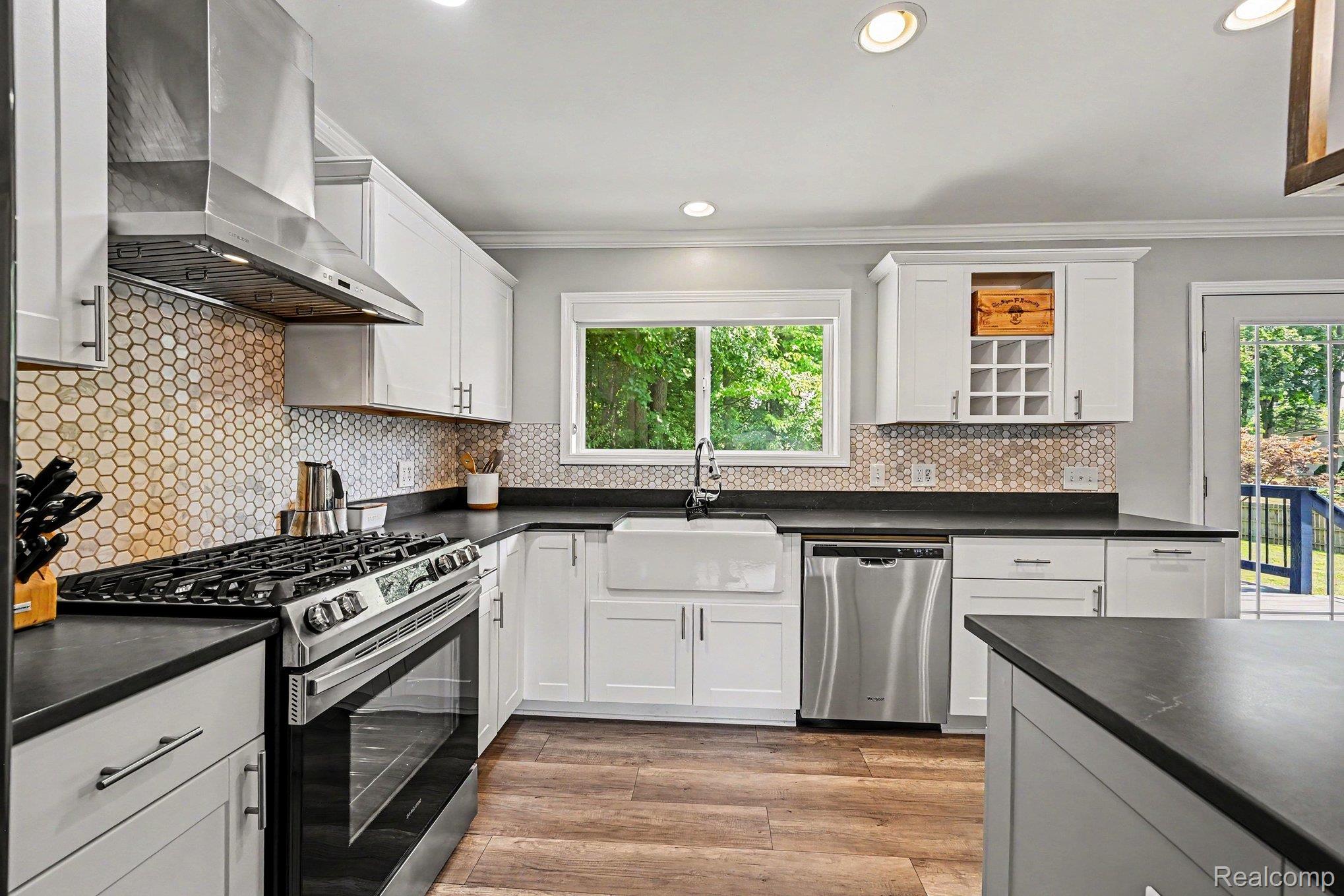 2104 Highfield Road Waterford, MI 48329 - Photo 8 of 38 Kitchen featuring shaker-style cabinetry, LVP flooring, a farmhouse sink, stainless steel appliances, and a honeycomb tile backsplash