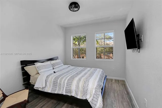 a bedroom with a bed a flat screen tv and window