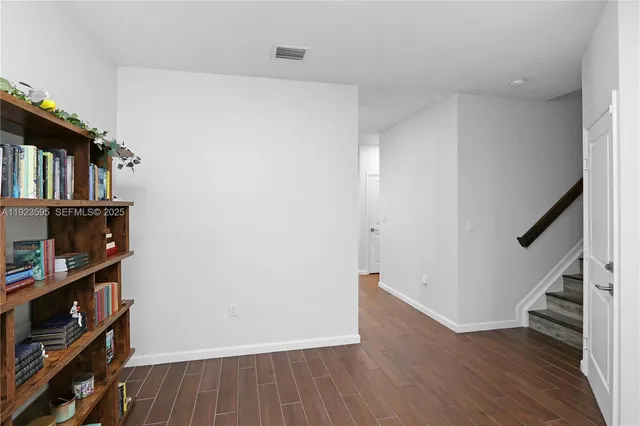 a view of an empty room with wooden floor and stairs