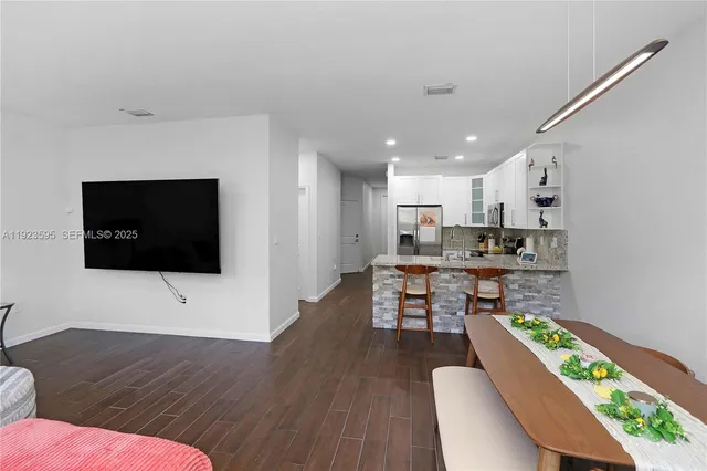 a living room with stainless steel appliances kitchen island furniture and a flat screen tv