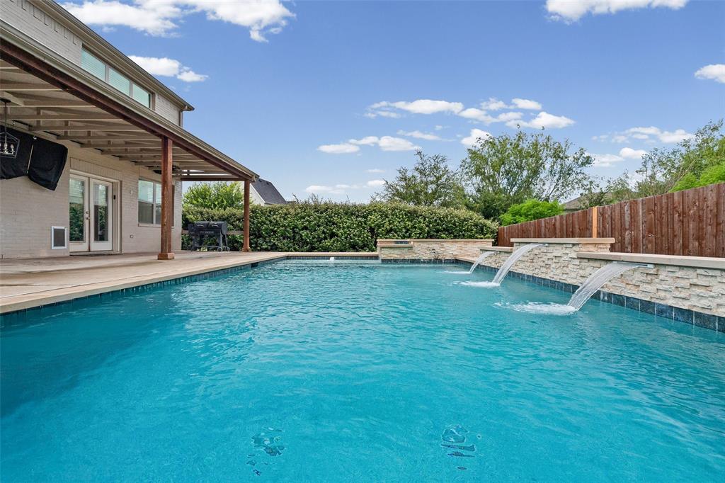 437 Prairie Run Aledo, TX 76008 - Photo 11 of 33 Water features on the pool, bordered by a stone accent wall and a wood fence