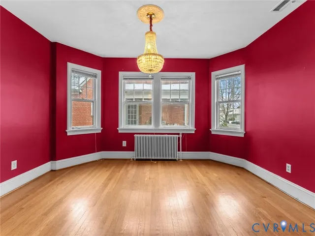 a view of an empty room with wooden floor and windows