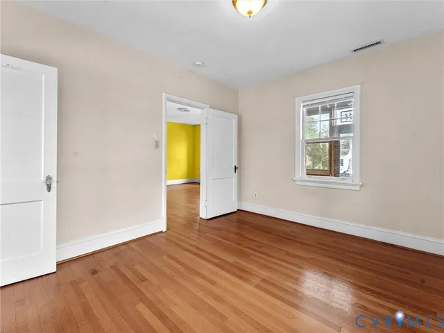 an empty room with wooden floor and window