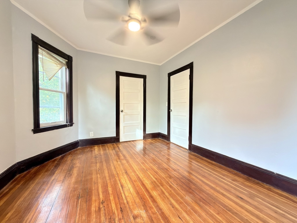 18 Harold Park, Unit 3 Boston, MA 02119 - Photo 15 of 41 an empty room with wooden floor chandelier fan and windows