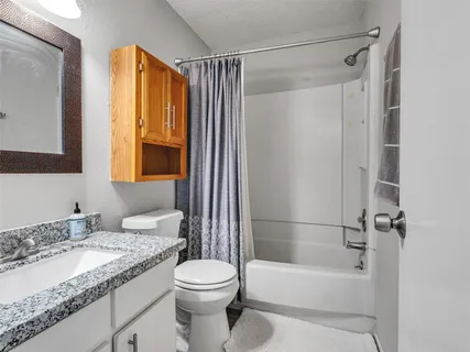 a view of an empty room with wooden floor and a fan