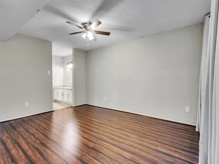 a view of room with hardwood floor and a ceiling fan