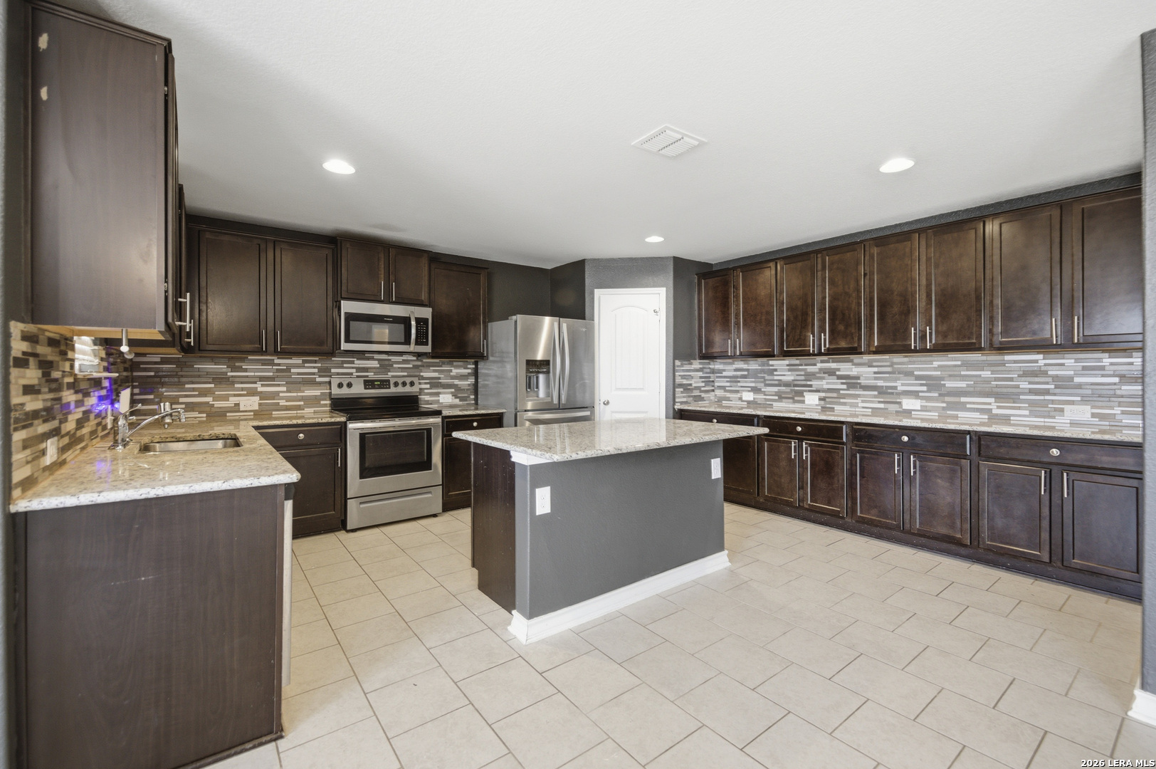 a kitchen with stainless steel appliances granite countertop a stove top oven a sink and a refrigerator