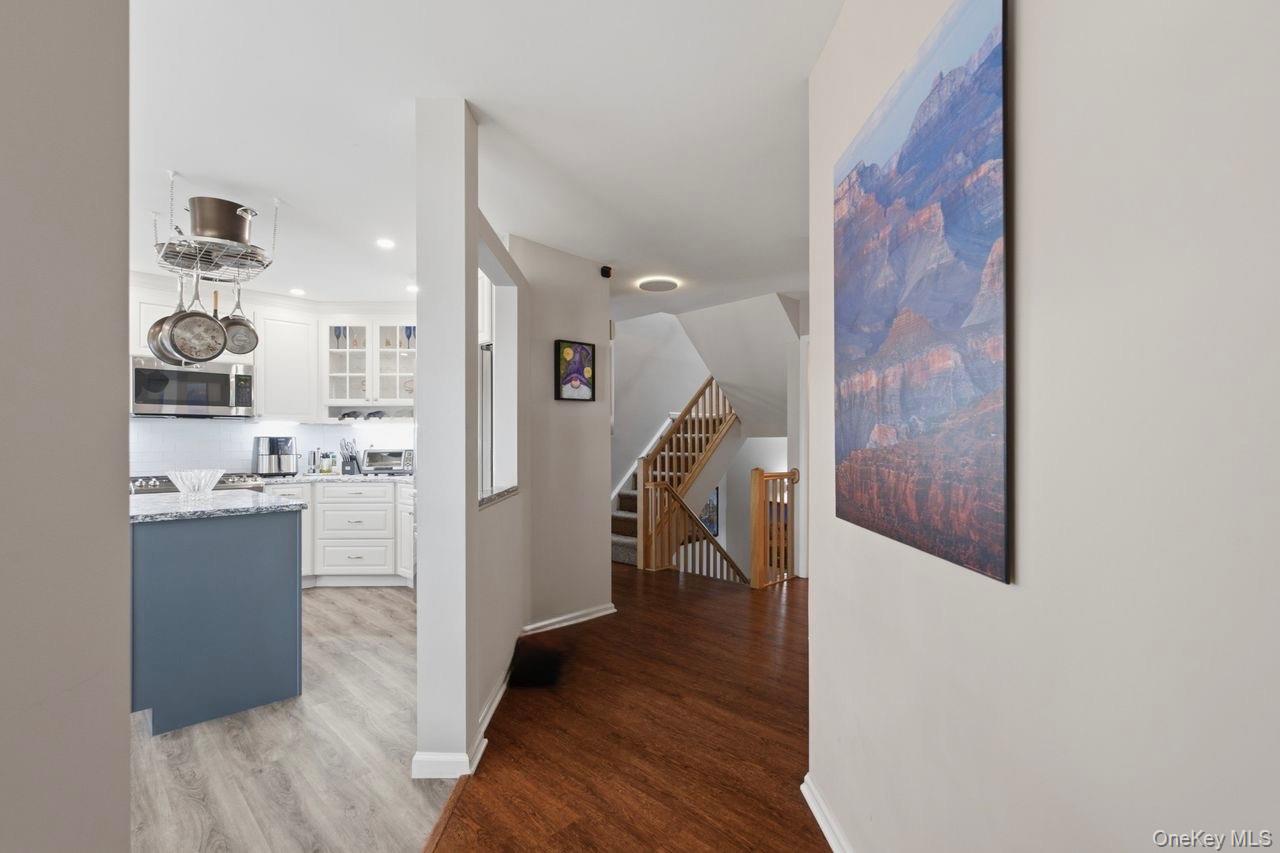 64 Roma Orchard Road Peekskill, NY 10566 - Photo 4 of 40 Kitchen featuring white cabinetry, stainless steel appliances, a blue-grey island with a light-colored countertop, and wood-finish flooring