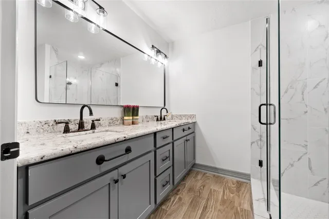 a bathroom with a granite countertop sink a mirror and shower